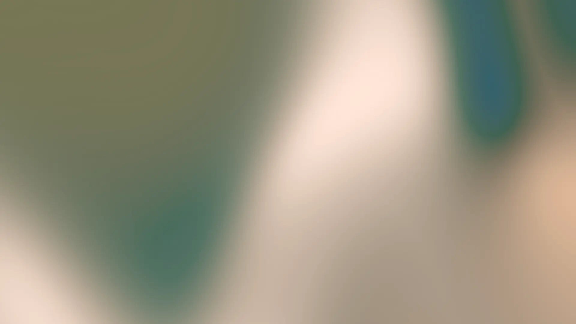 An abstract, heavily blurred background with soft gradients of muted green, teal, cream, and pale peach.