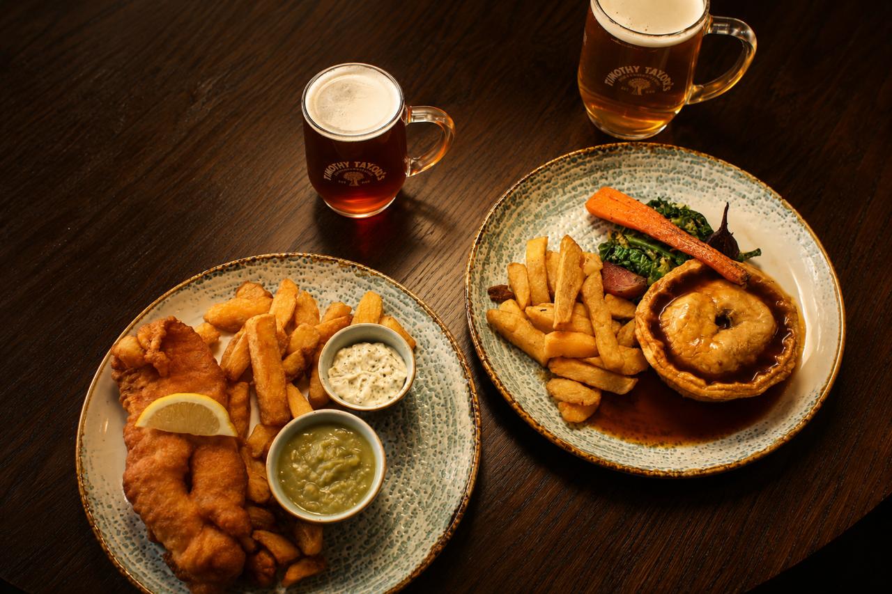 Two plates of food with drinks on a wooden table