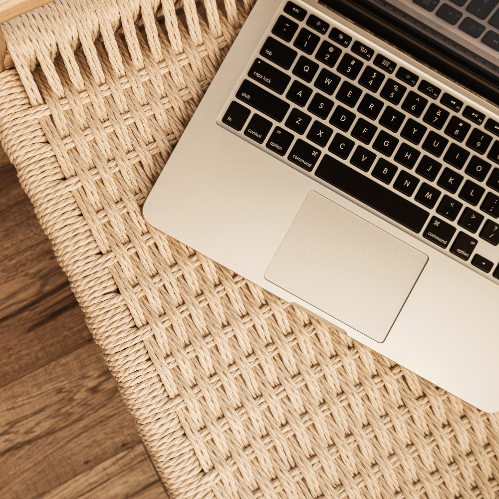 Laptop on a woven mat with wooden floor background