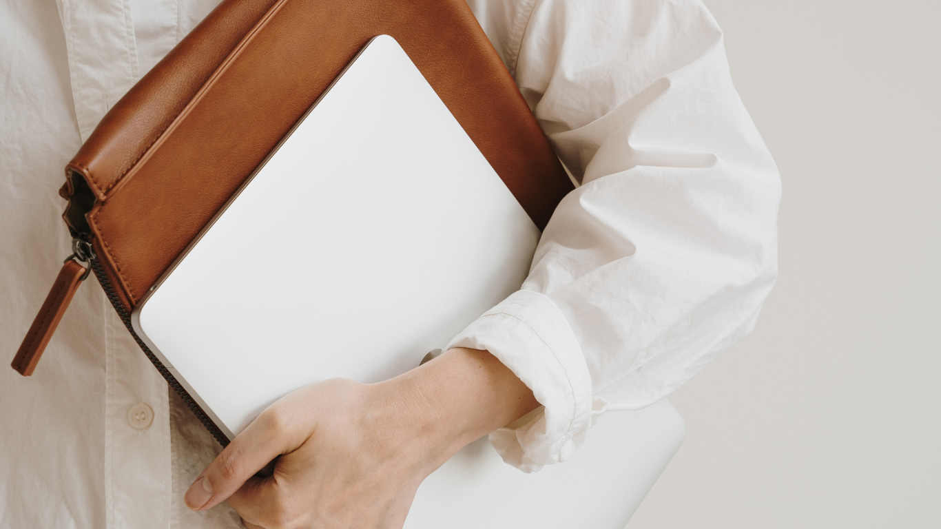 Person holding a brown and white leather clutch bag