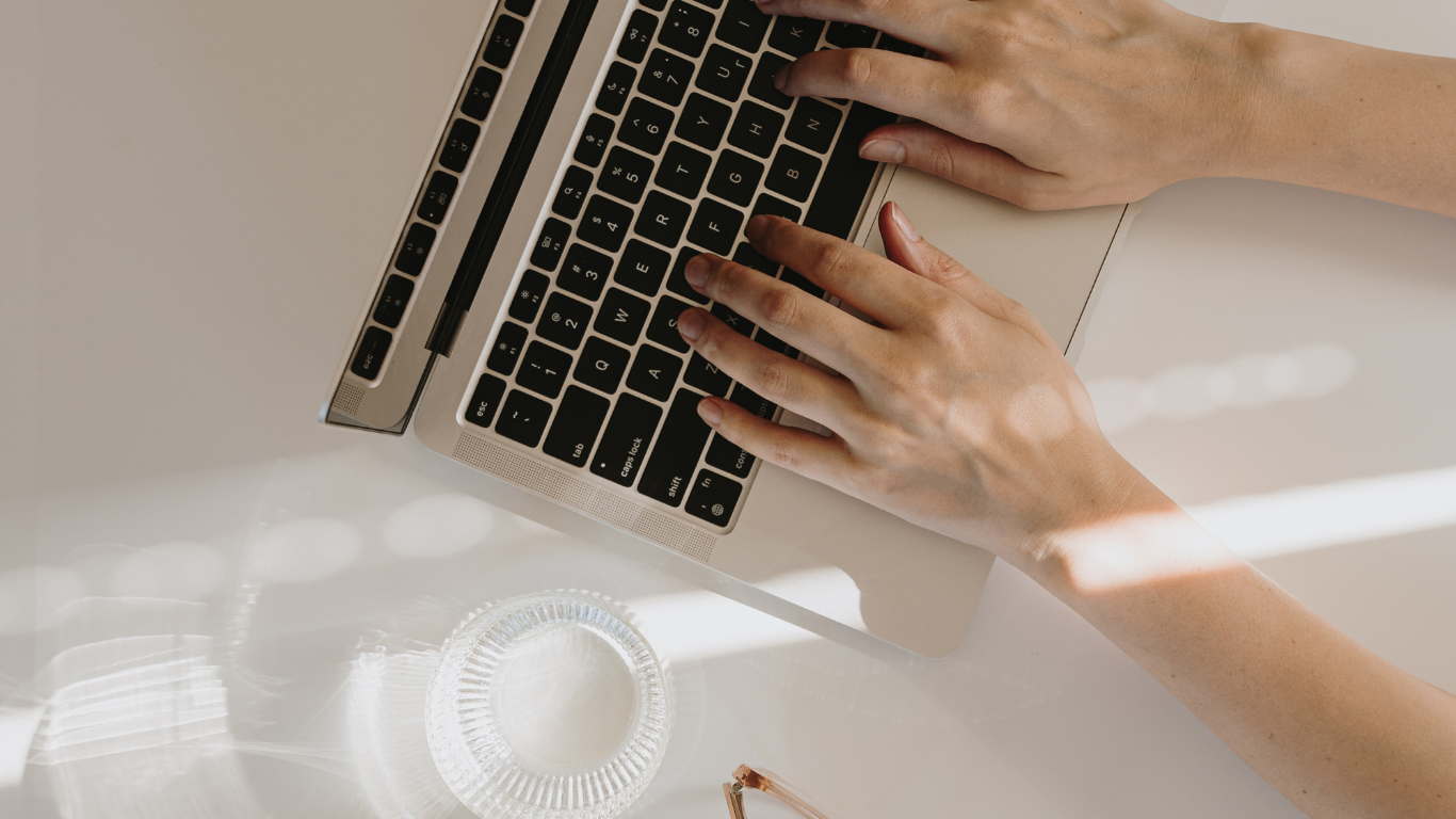 Person typing on a laptop with a blurred indoor background