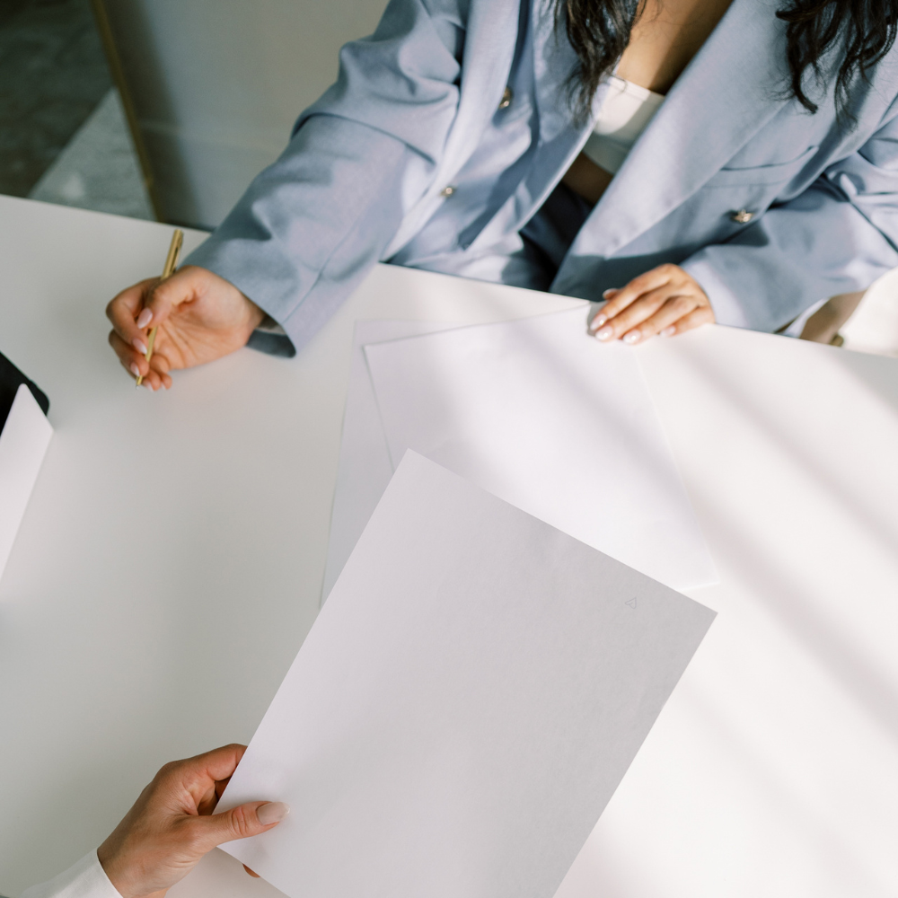 Two people working on a large sheet of paper with a pencil.