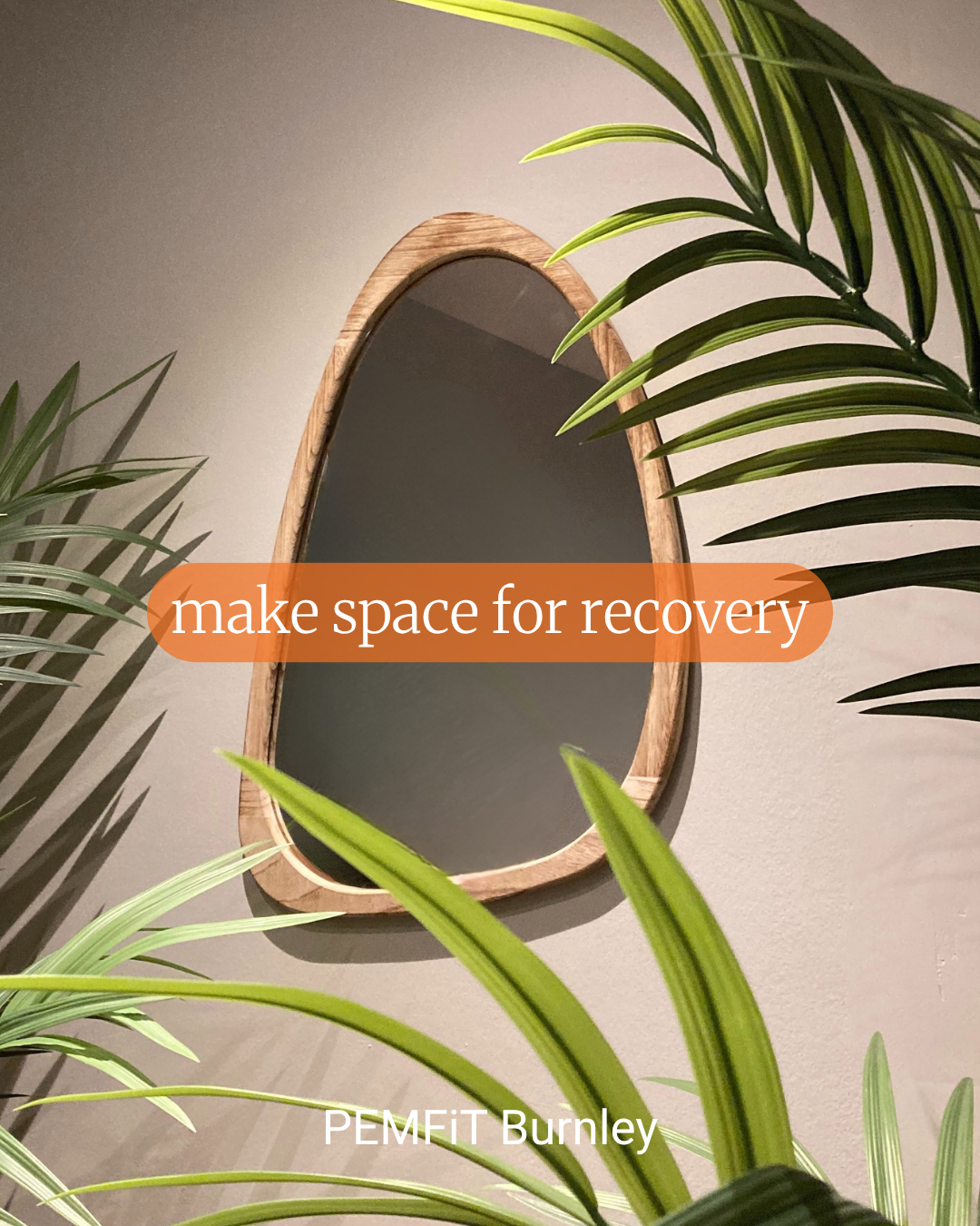 Wooden mirror with green plants on a beige wall, featuring text 'make space for recovery' and 'PEMFIT Burnley'.