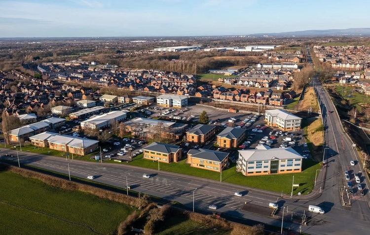 Aerial view of a suburban area with roads, buildings, and green spaces.